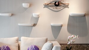 Een moderne woonkamer met een bank, een rode fauteuil en een hangklok.