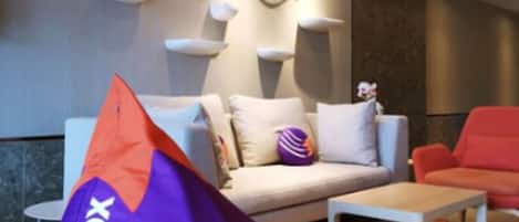A modern living room with a sofa, a red armchair, and a purple bean bag chair labeled "LAZY FOX".