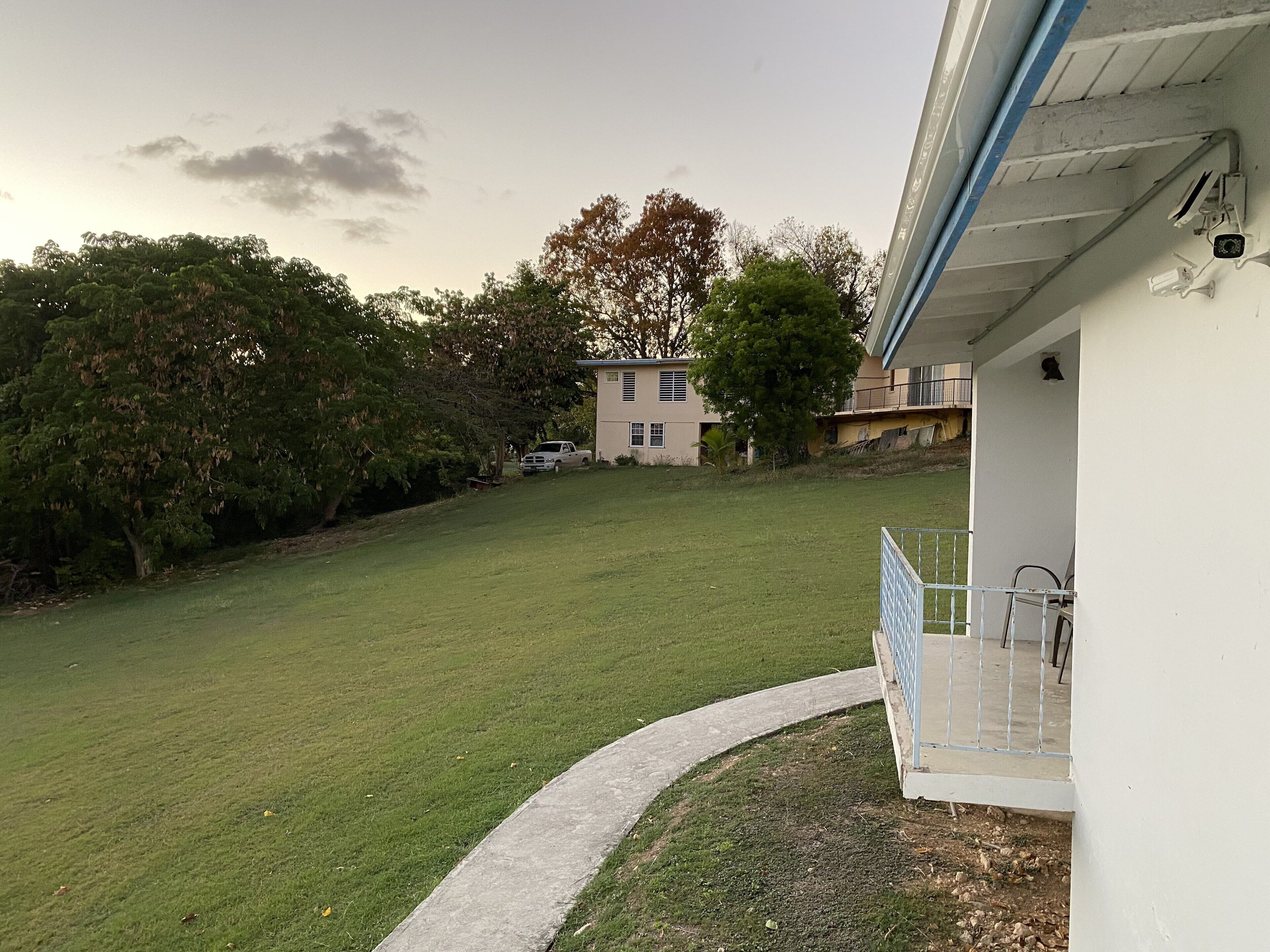 A grassy yard with a white building, a tree, and a parked truck.