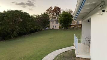 A grassy yard with a white building, a tree, and a parked truck.