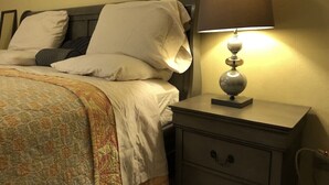Un lit bien fait, avec une couverture à motifs, une lampe de chevet et une table de chevet dotée de tiroirs.