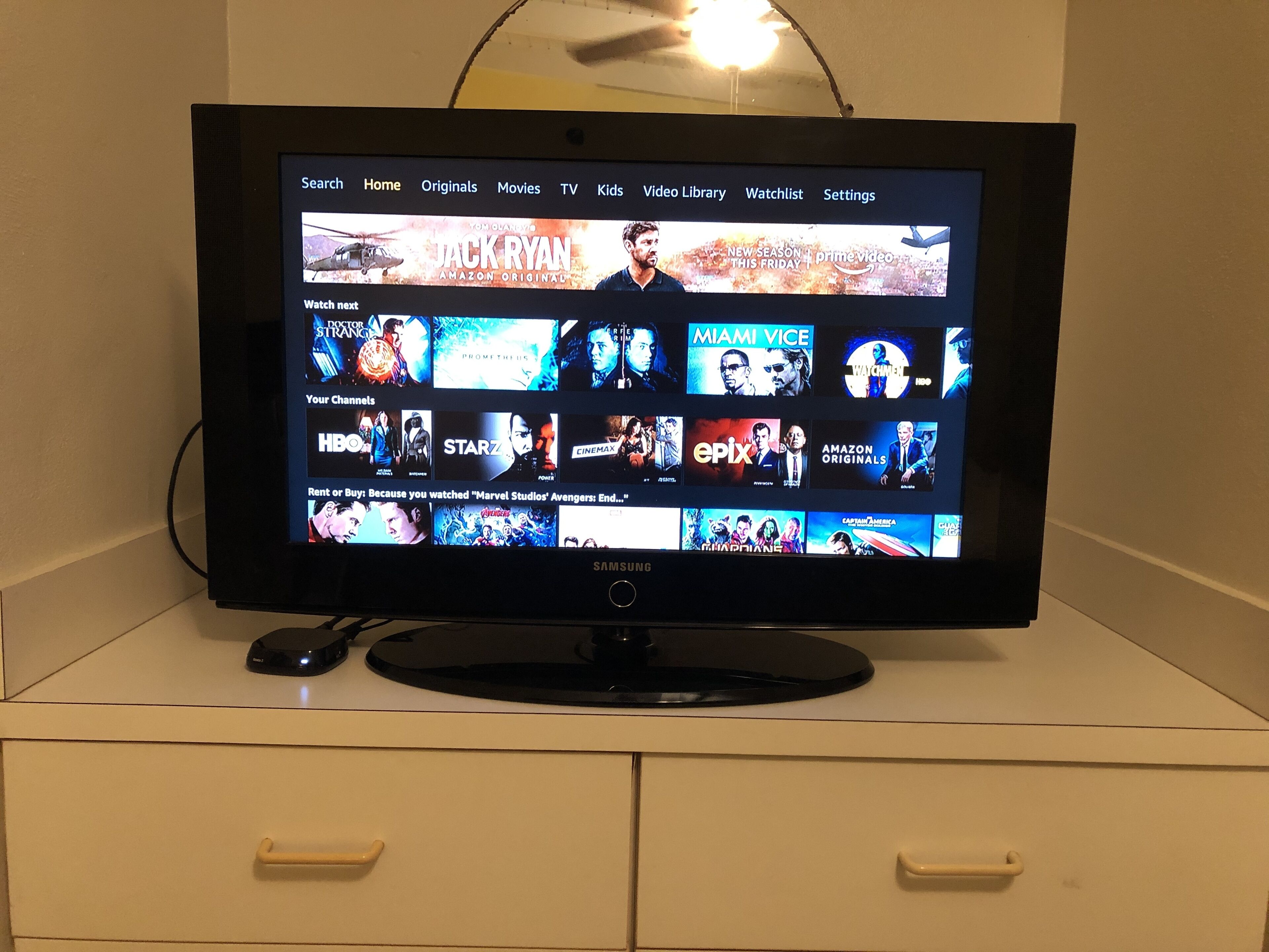 Een flatscreen televisie op een wit kastje, met een aangesloten kabel.