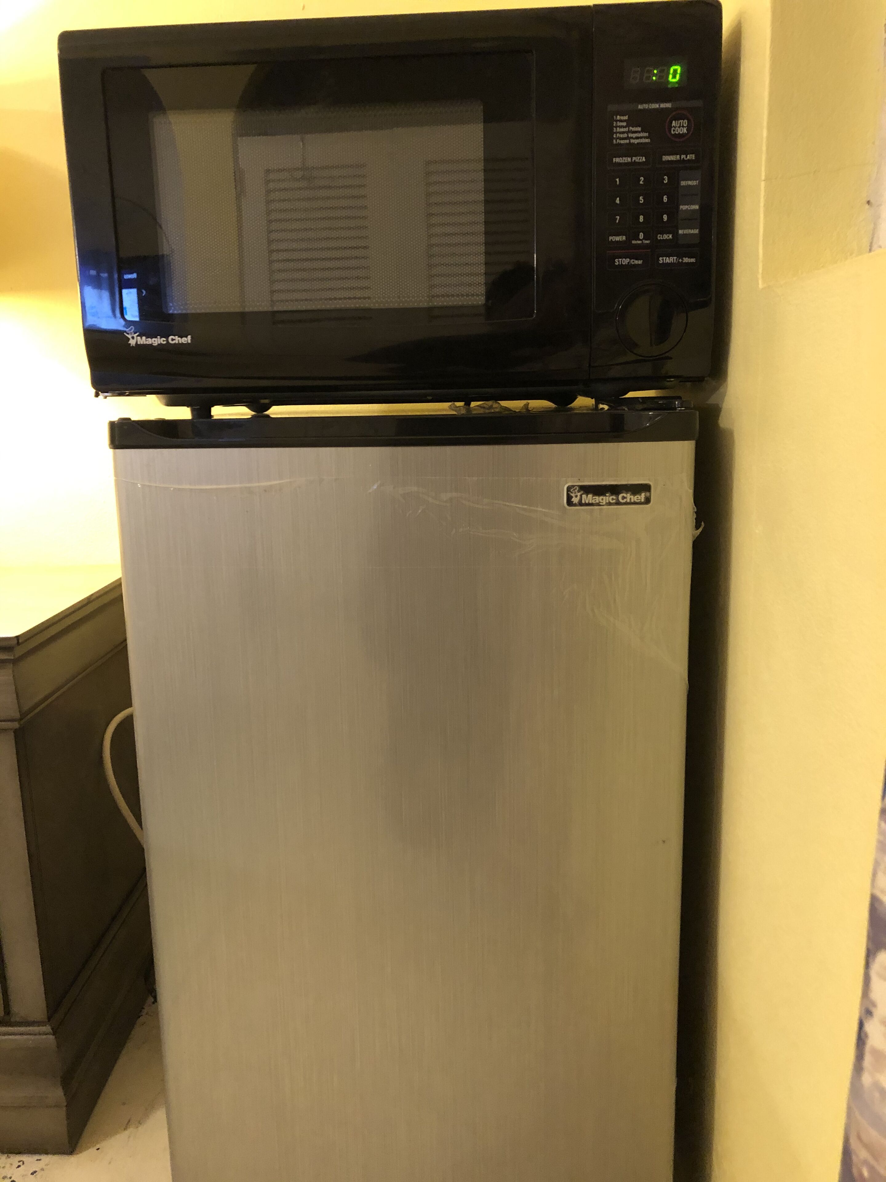 Um frigorífico compacto com micro-ondas embutido em cima.