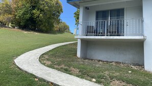 Un bâtiment avec un chemin en béton menant à un balcon doté d’une rambarde en métal.