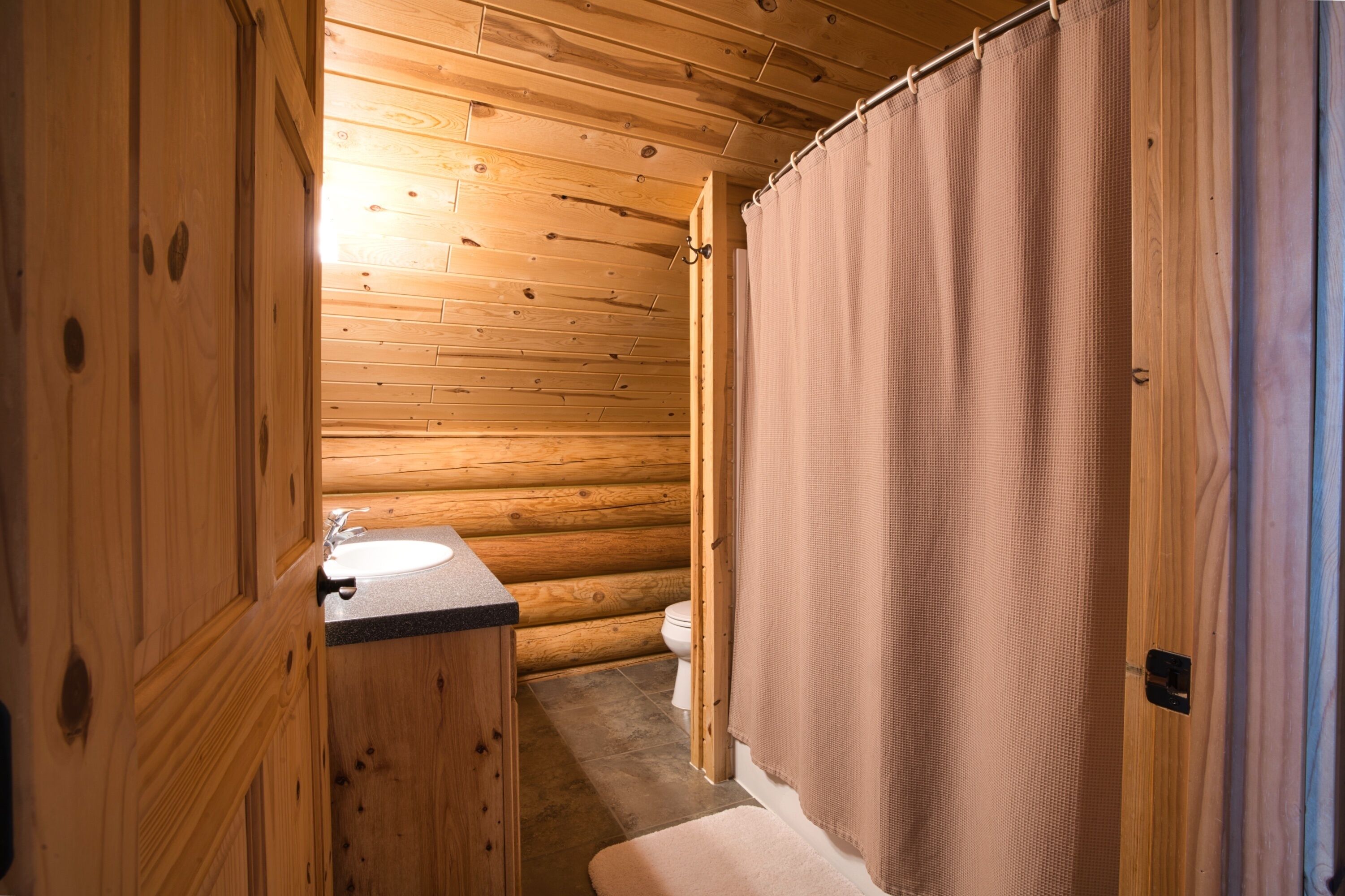 A wooden cabin bathroom with a wooden sink and toilet.