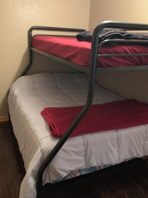 Un letto con un materasso bianco e una coperta rossa.