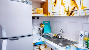 Eine kleine Küche mit Kühlschrank, Mikrowelle, Spüle und einem blauen Schneidebrett.