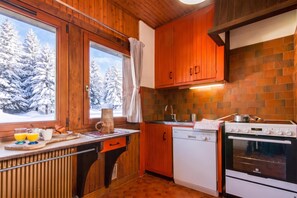Une cuisine avec des meubles de rangement en bois, une cuisinière et un évier.