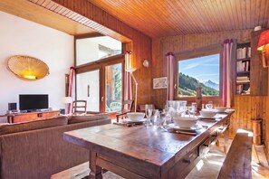 Un intérieur en bois comprenant une table à manger pour quatre personnes, un téléviseur et une bibliothèque.