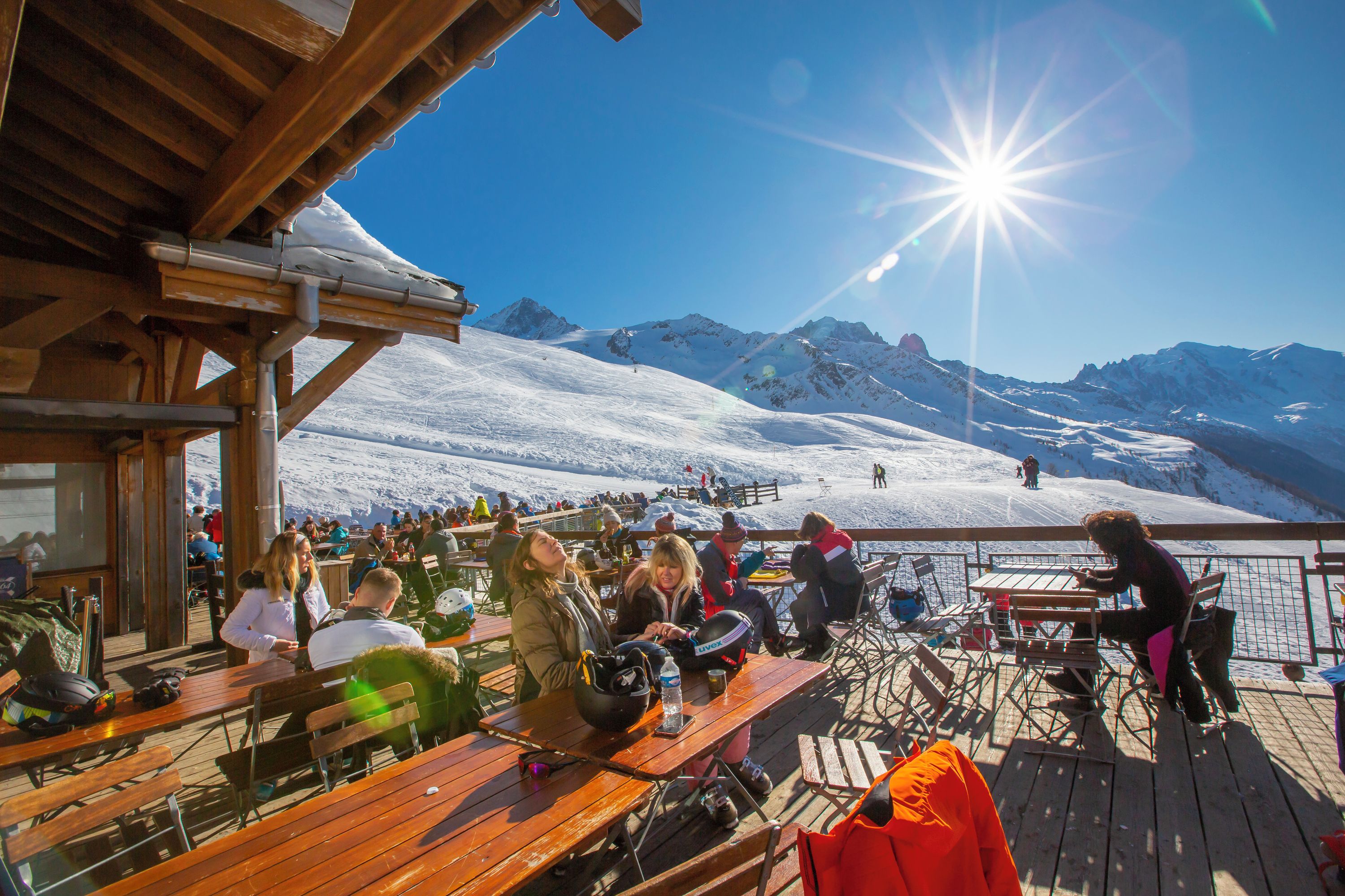 A wooden deck with tables and chairs overlooking a snowy mountain landscape.