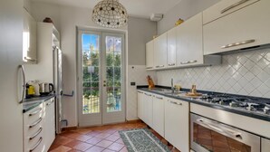 A kitchen with white cabinets, a gas stove, a refrigerator, and a patterned rug.