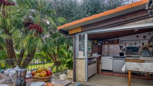 An outdoor kitchen with a dining area, surrounded by palm trees and a garden.