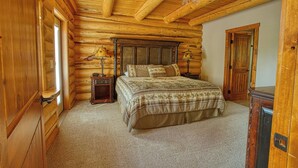 A log cabin bedroom with a bed, wooden walls, and a wooden ceiling.