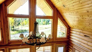A log cabin interior with a large skylight, multiple windows, and a chandelier.