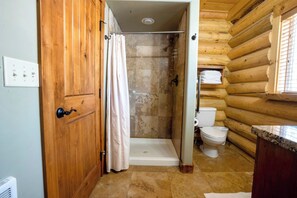 A wooden cabin bathroom with a shower, toilet, and a wooden door.