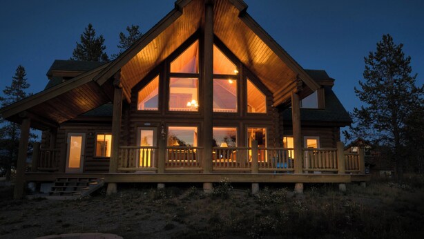 A log cabin with a large front porch and multiple windows.