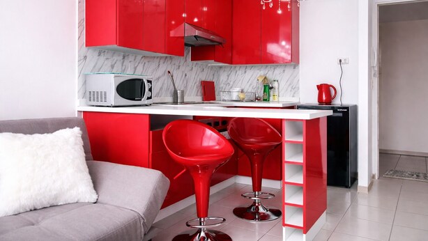 Una cocina moderna con armarios rojos, una encimera blanca, un microondas y una cafetera.
