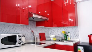Una cocina moderna con armarios rojos, una campana extractora de acero inoxidable, un microondas y un lavamanos.