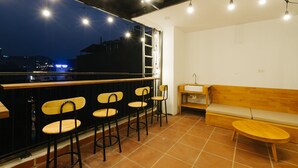 A rooftop bar with four wooden bar stools, a wooden bench, and a small table. A ladder is visible against the wall. - The Eighty8 Hanoi Hostel (Hanoi)