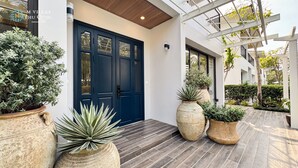 A modern villa with a dark blue front door, large potted plants, and a wooden deck. - M Villas Phu Quoc (Phu Quoc)