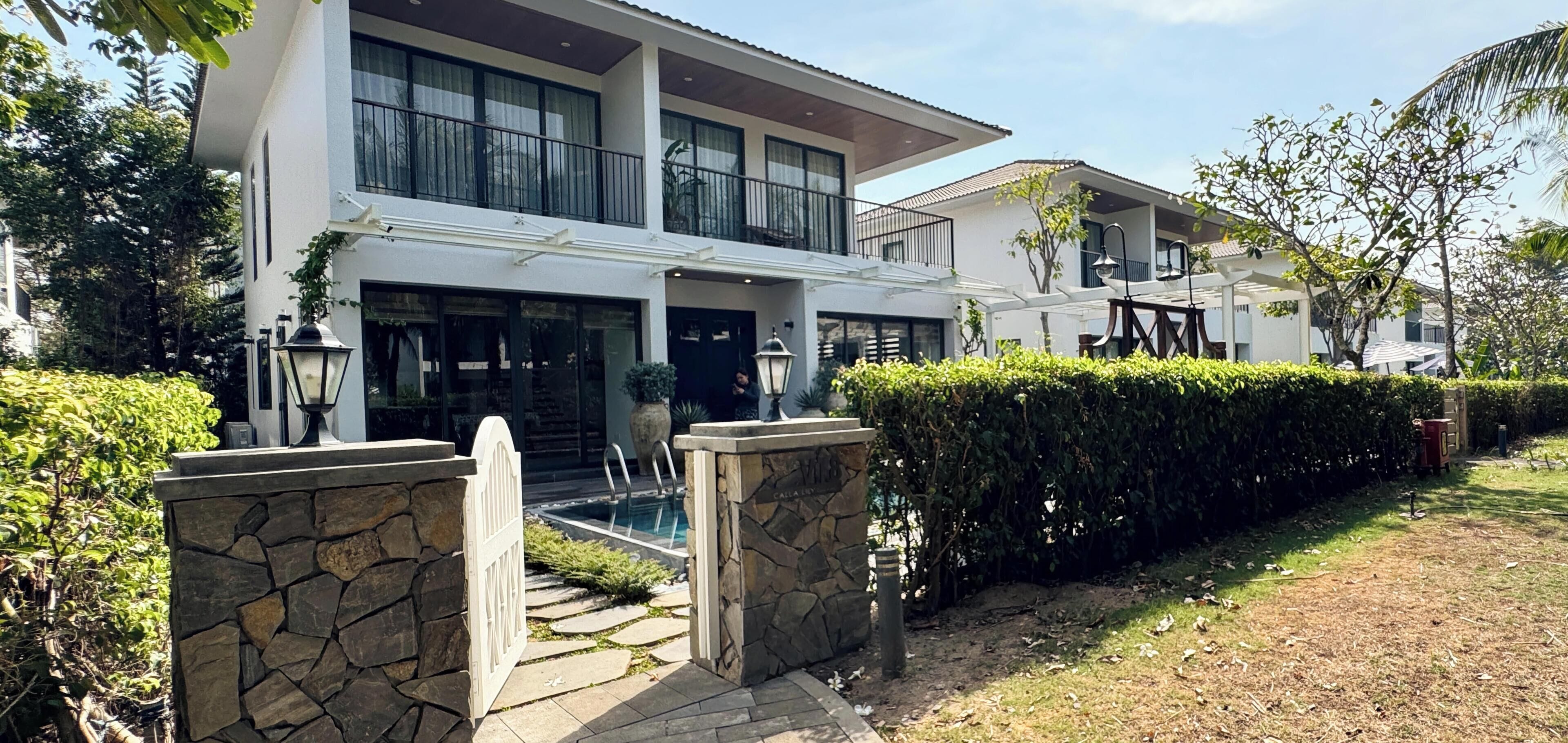 Uma casa moderna com dois andares, entrada em pedra, piscina e um jardim bem cuidado.