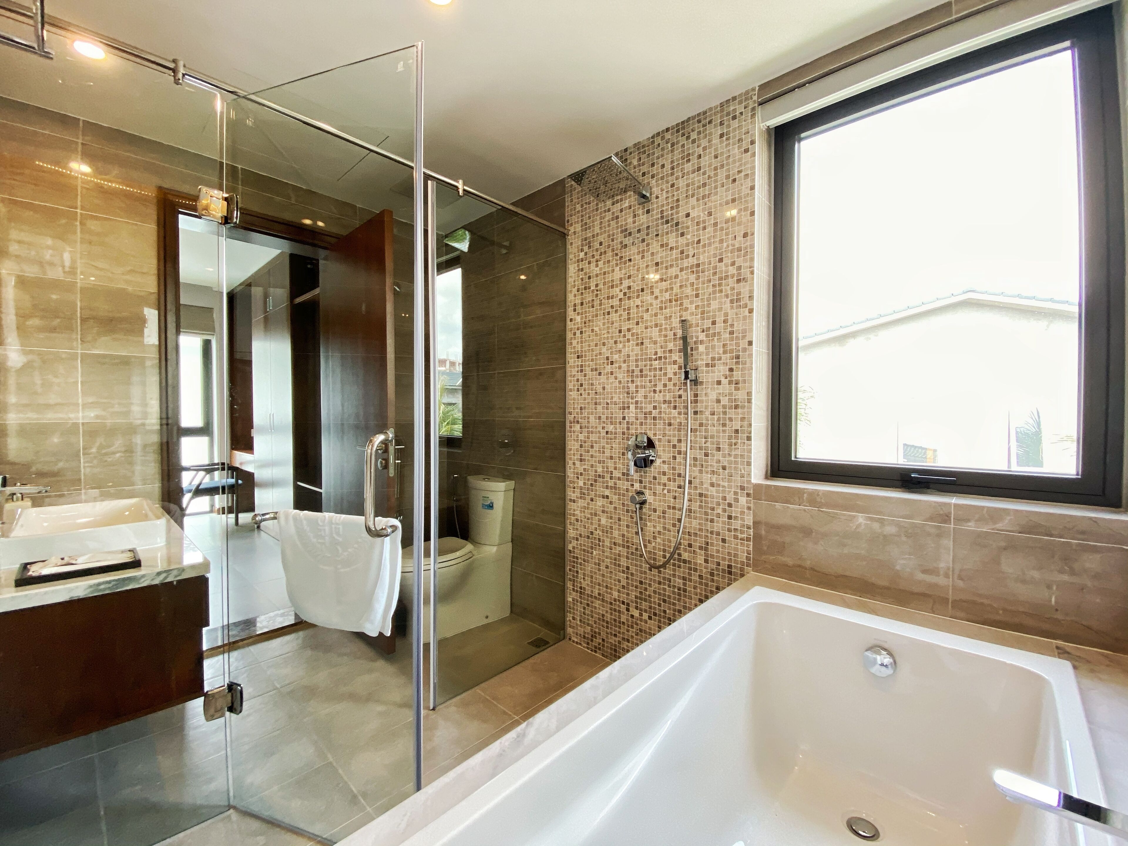 Ein modernes Badezimmer mit einer gläsernen Duschkabine, einer großen Badewanne und einem WC.