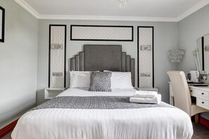 Une chambre d’hôtel avec un grand lit, un bureau avec une chaise, un miroir et un radiateur.