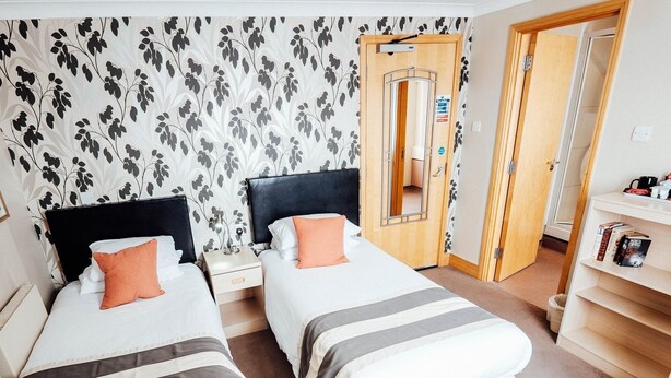 Una habitación de hotel con dos camas, un armario, un espejo y una estantería.