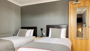 Habitación de hotel con dos camas, un armario de madera y un espejo.