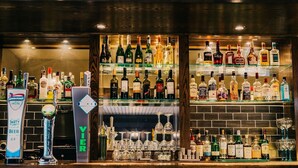 Una barra con estantes llenos de botellas de licor y una grifería de cerveza.