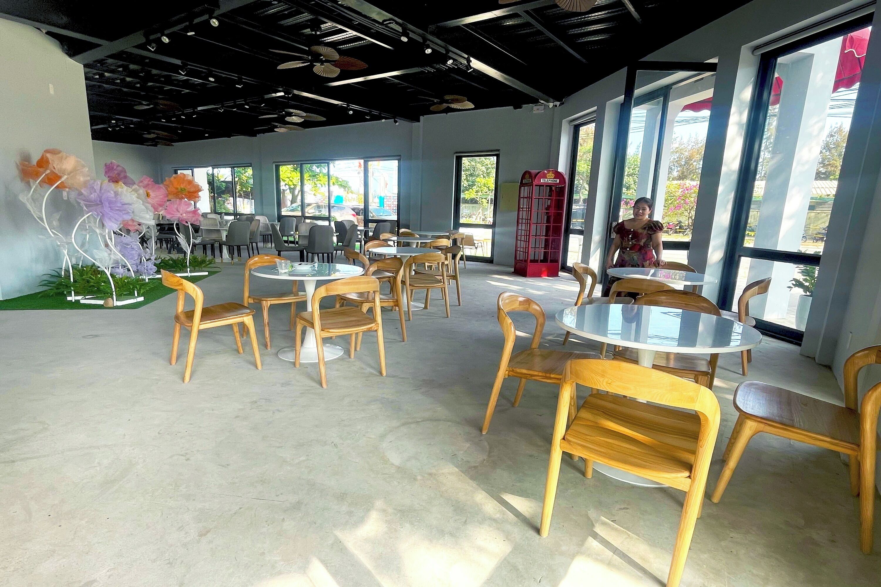 A spacious indoor area with round tables and wooden chairs, large windows, and a red telephone booth.
