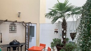 A patio with a grill, folding table, chairs, potted plants, and a ladder against a wall. - GITE 7/8 P. LE NAPOLEON, Not suitable for PRMs (Saint-Leu-la-Forêt)