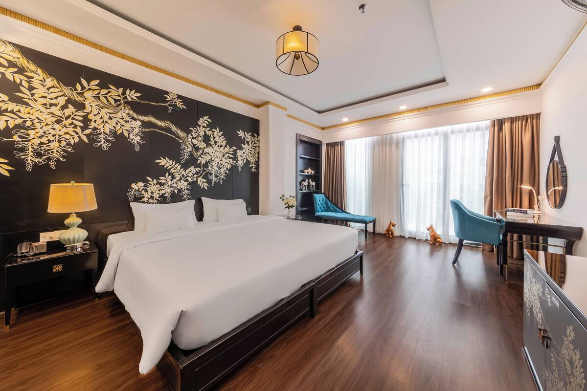 Ein Hotelzimmer mit einem großen Bett, einem Schreibtisch, einem Sessel und einer Wandverziierung.