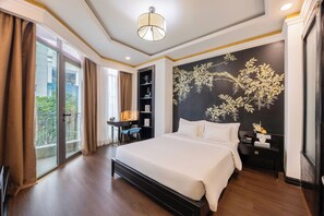 Een hotelkamer met een groot bed, een bureau met stoel, een boekenplank en een decoratieve wand.