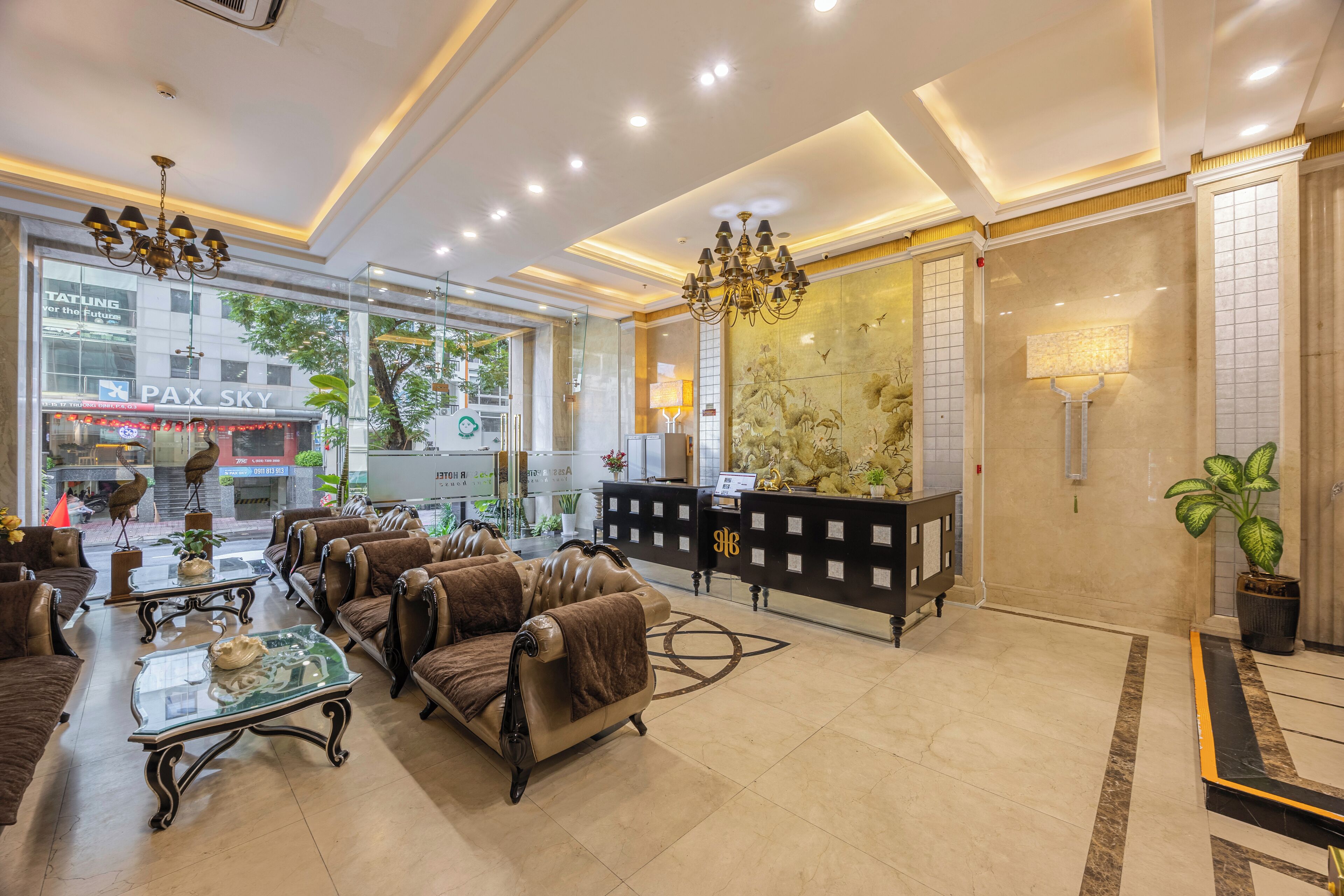 A hotel lobby with leather sofas, a reception desk, and a chandelier.