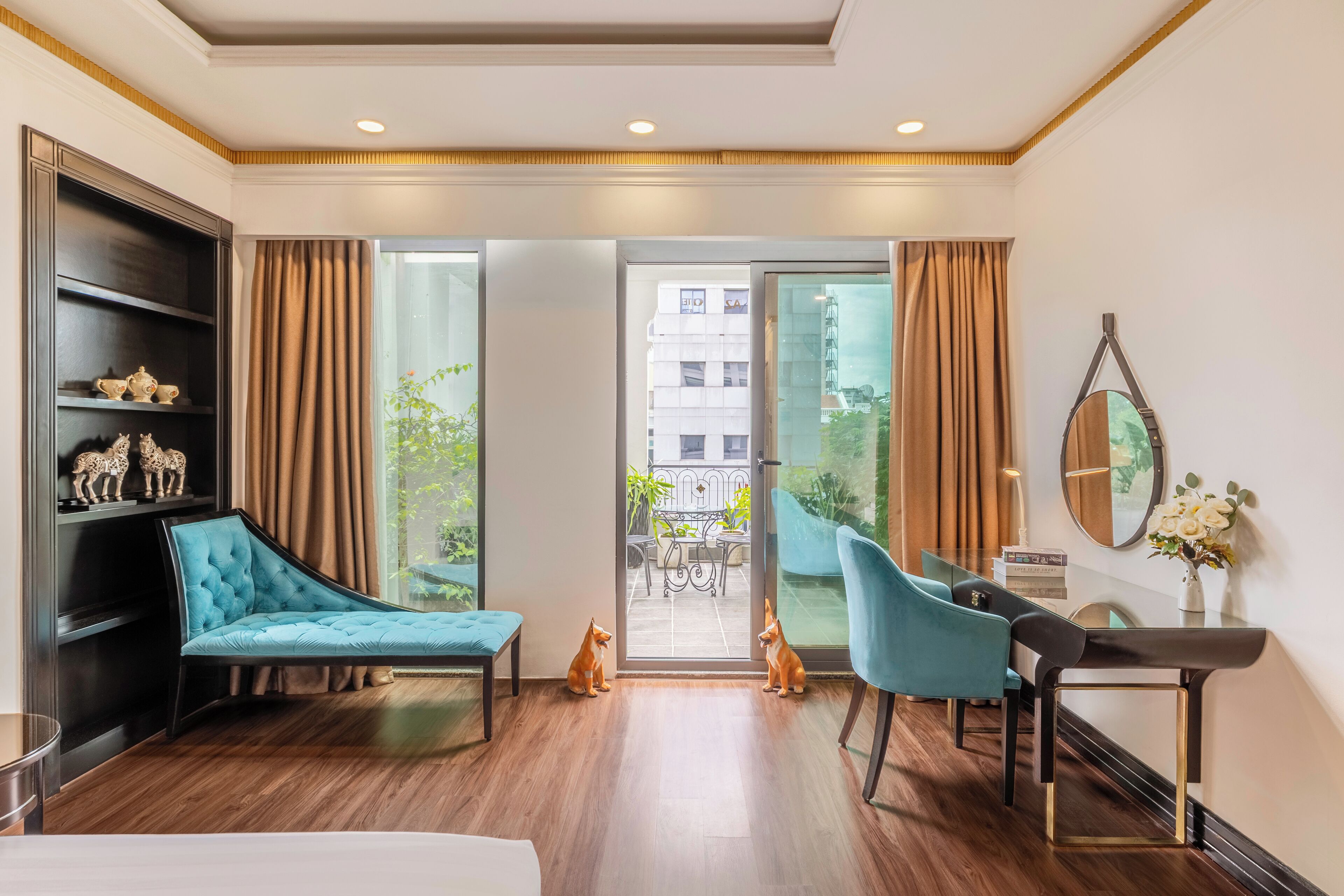 A modern hotel room with a sofa, a desk, and a view of the outdoor balcony.