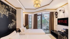Une chambre d’hôtel avec deux lits, une grande fenêtre, un téléviseur fixé au mur et un balcon offrant une vue sur la ville.