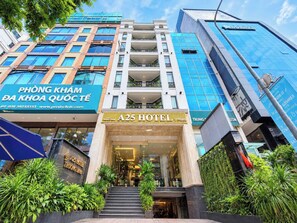 A hotel entrance with a modern facade, a visible staircase, and lush greenery around the base. - A25 Premium Hotel - 06 Truong Dinh (Ho Chi Minh City)