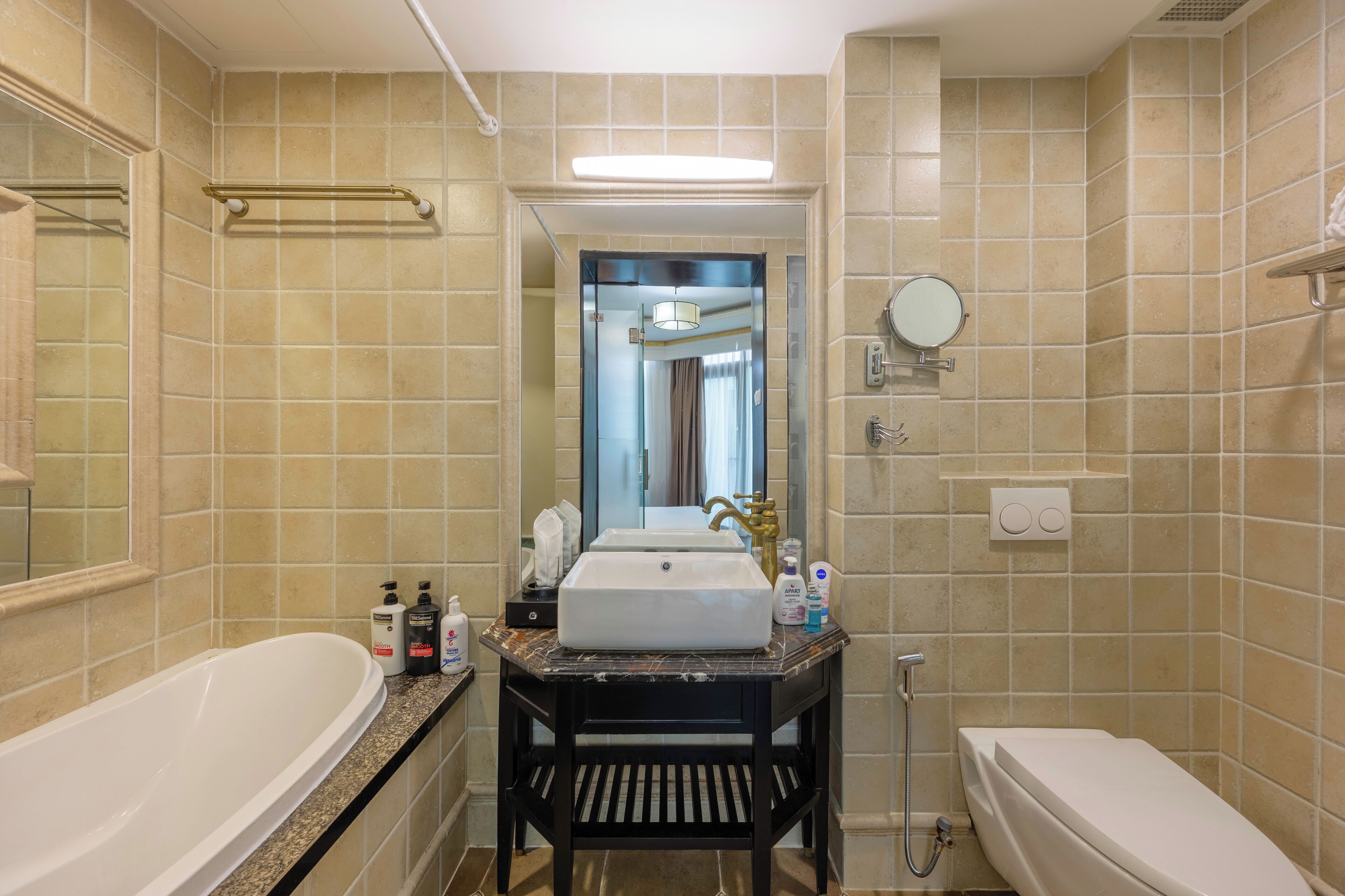 A bathroom with a bathtub, a sink with a vanity, a mirror, and a shower area.