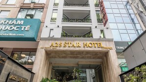 L’entrée de l’hôtel A25 Star se distingue par sa façade moderne, un escalier menant à l’entrée et la verdure environnante.