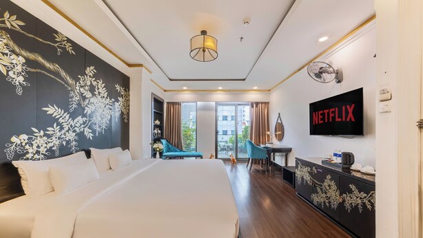 Une chambre d’hôtel moderne avec un grand lit, une télévision et un balcon offrant une vue agréable.