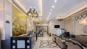 Un hall d’hôtel comprenant un comptoir d’accueil, des canapés, un lustre et une horloge murale.