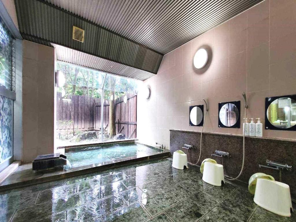 Un baño con una bañera grande, zona de ducha e lavamanos con espejos.