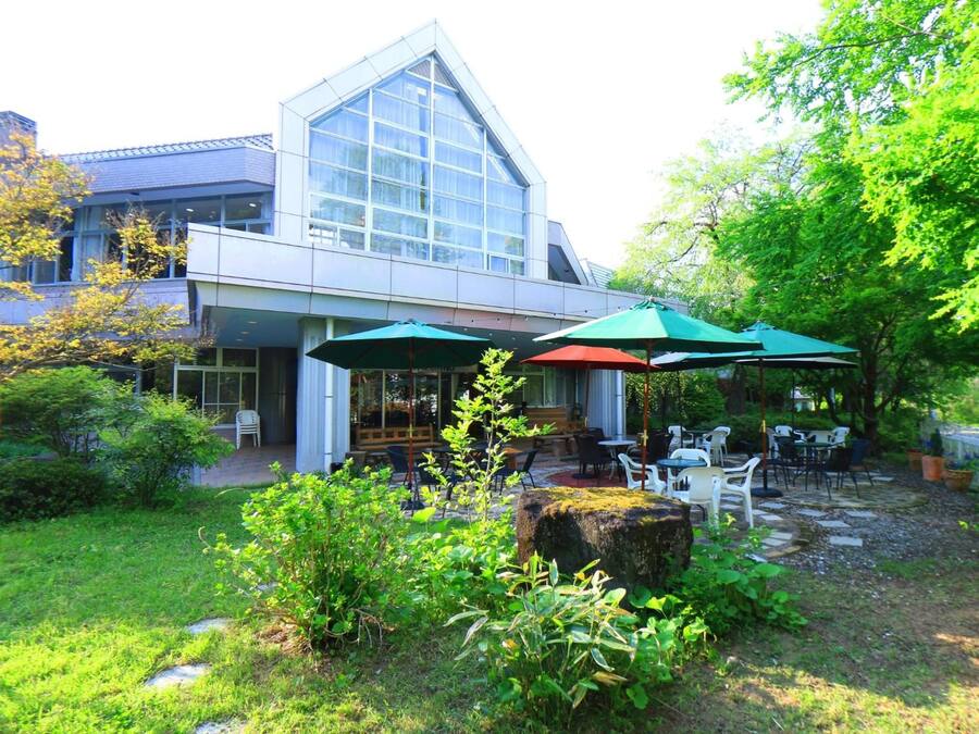 Un edificio moderno con facciata in vetro e un patio con posti a sedere all'aperto e ombrelloni.