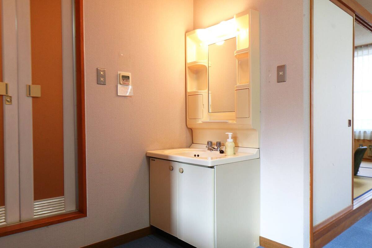 Een kleine hotelbadkamer met een wastafel, spiegel en een lampje op de muur.