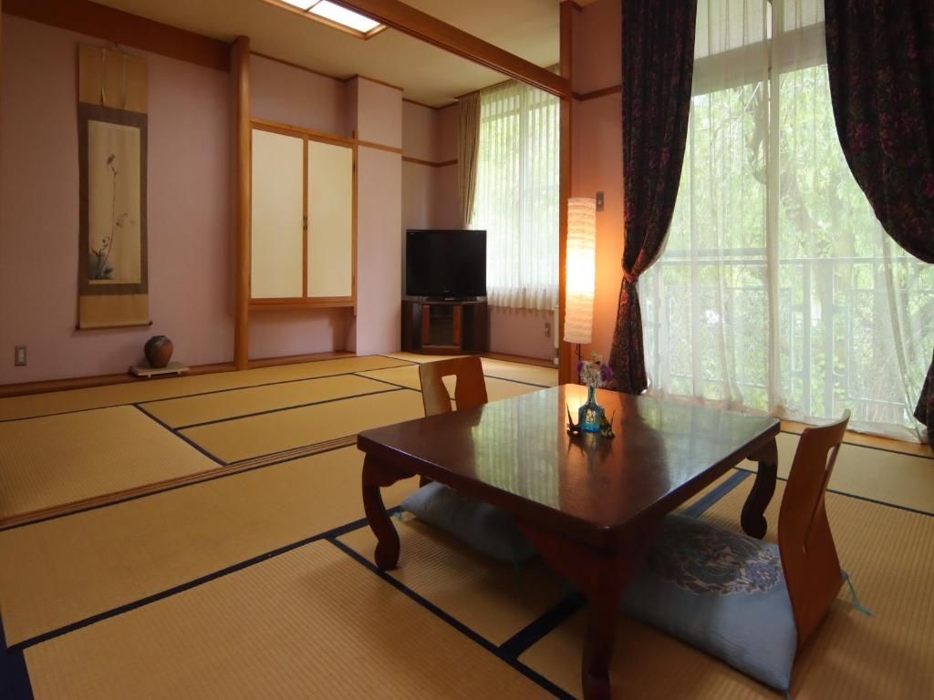 A traditional Japanese room with tatami flooring, a low table, and a television.