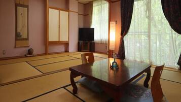 A traditional Japanese room with tatami flooring, a low table, and a television.