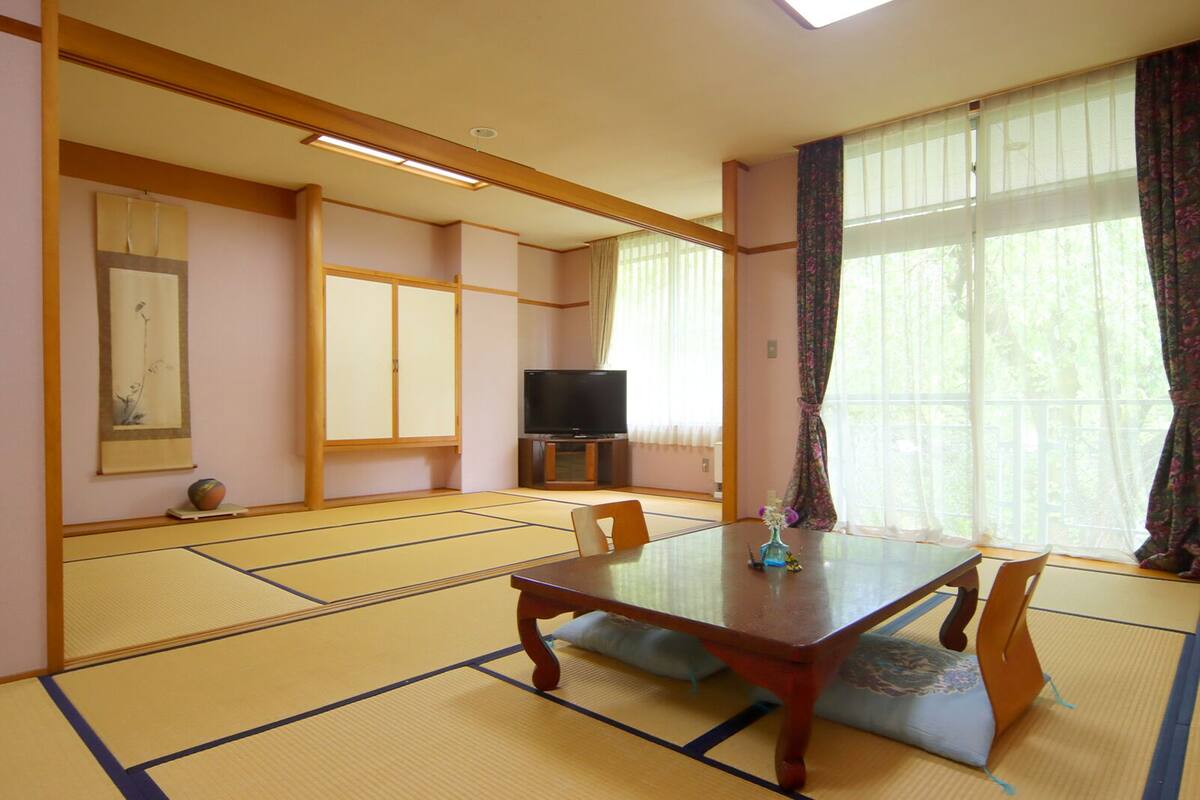 Een traditionele Japanse kamer met tatami vloerbedekking, een lage houten tafel en een televisie.