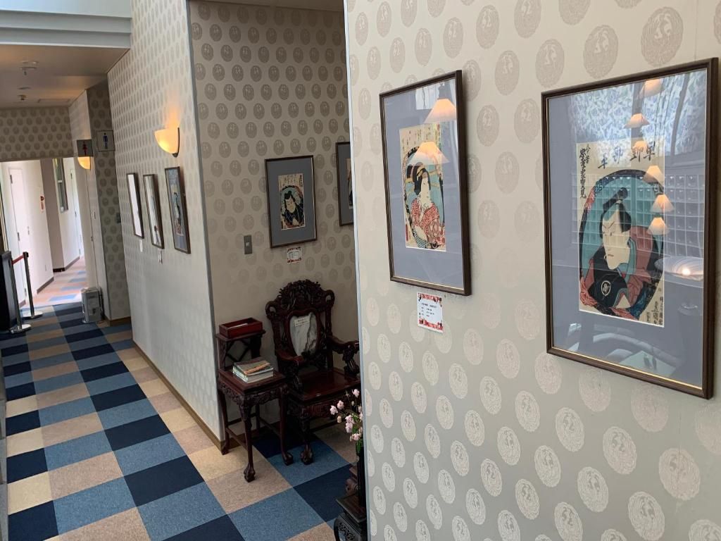 A hallway with patterned wallpaper, framed artwork, and traditional furniture.