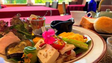 A dining table with a variety of dishes, including a plate with cheese, vegetables, and a pink flower garnish.